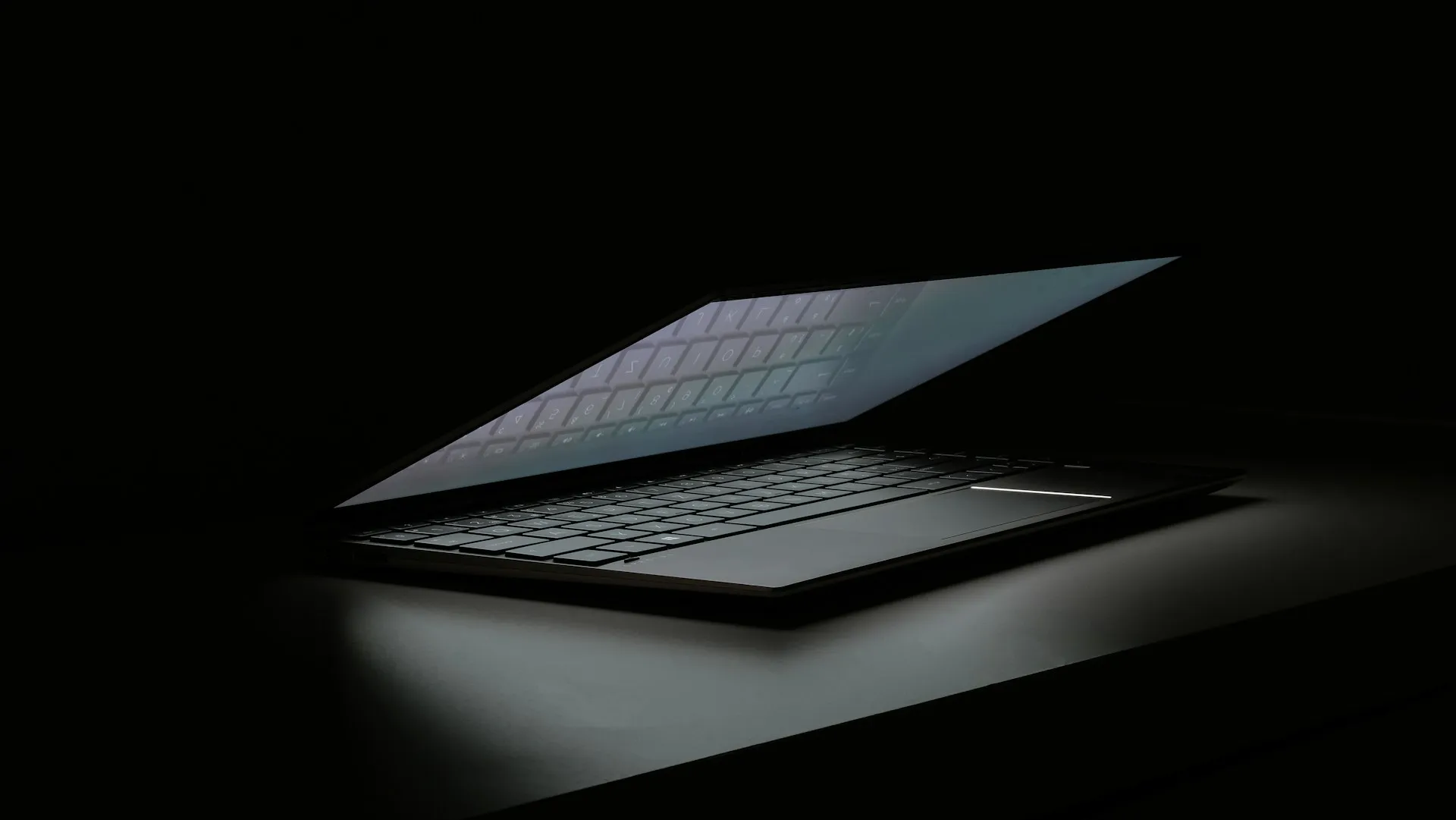 Single laptop on top of a desk within a dark setting 