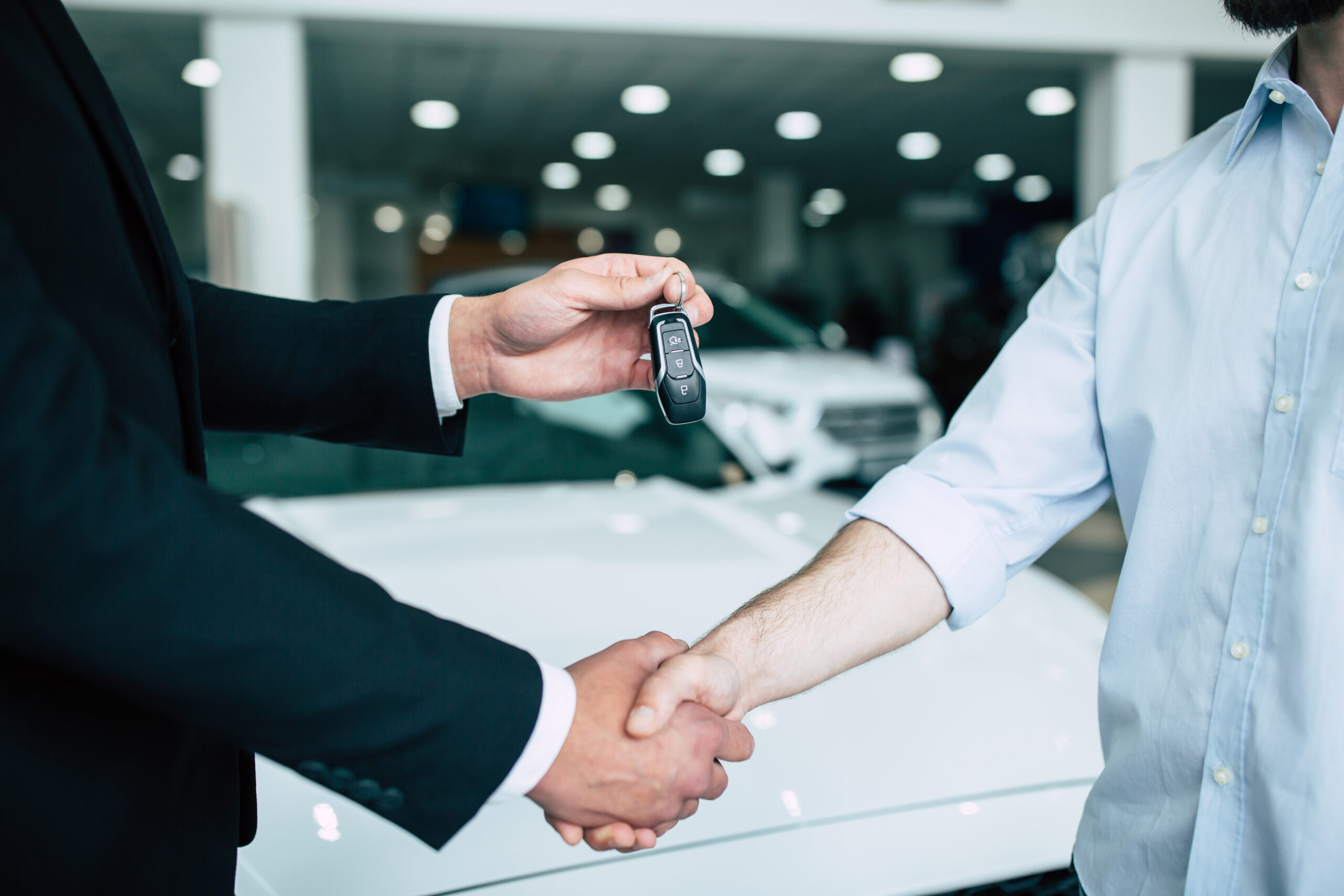 Buying a new car. Handshake and handing over the keys to the car by the sales consultant to the buyer. FICO® Auto Scores.
