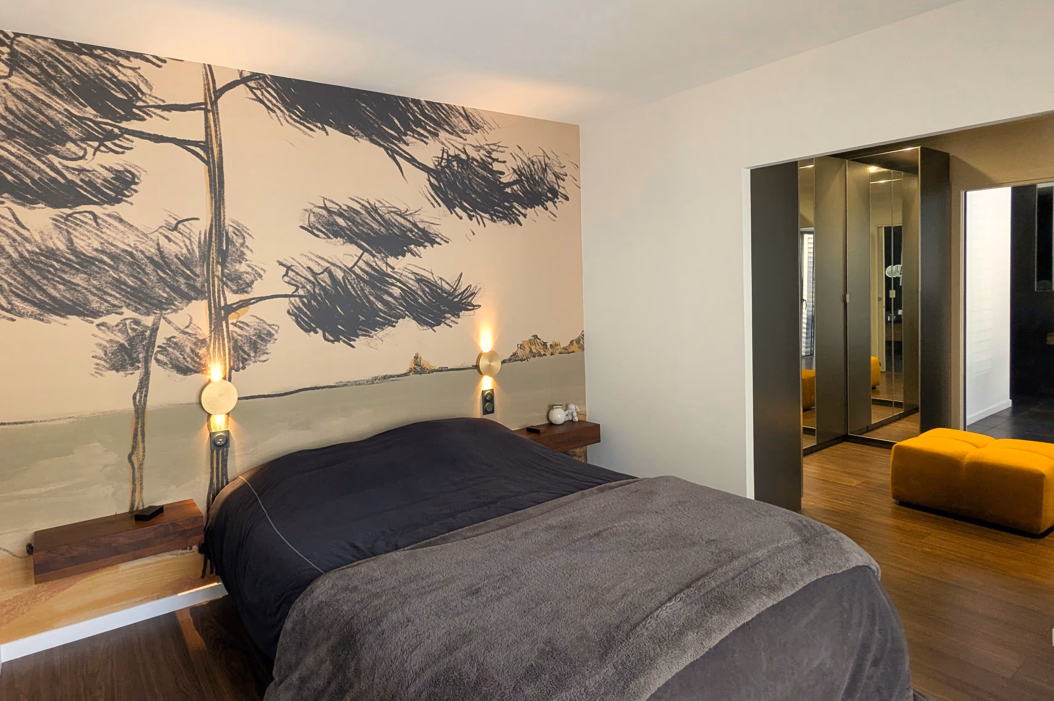 Chambre avec lit noir, appliques murales et fresque d'arbre peinte au mur, réalisation Cocoon