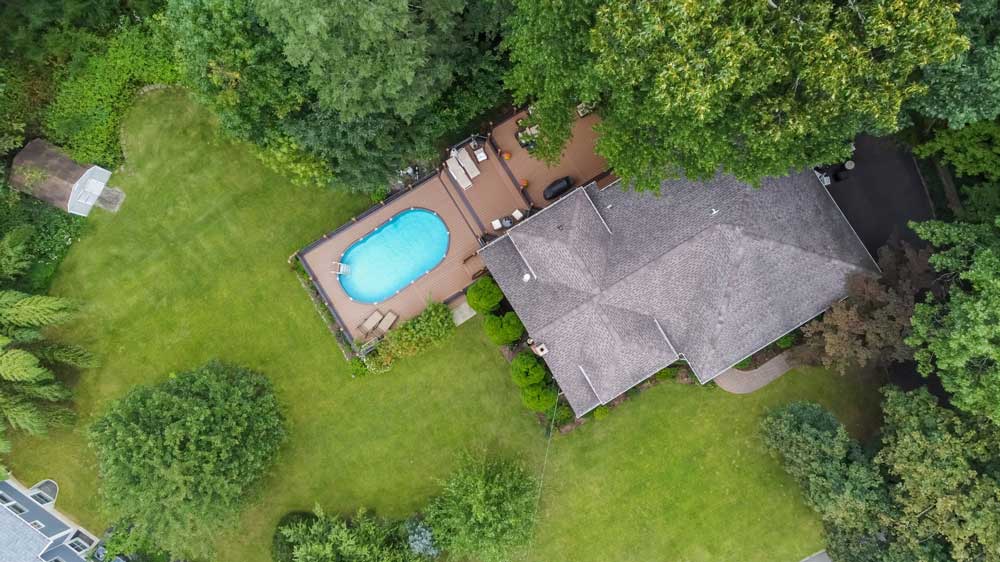 Aerial drone photo of a residential property with private pool and large backyard, captured for luxury real estate listing.