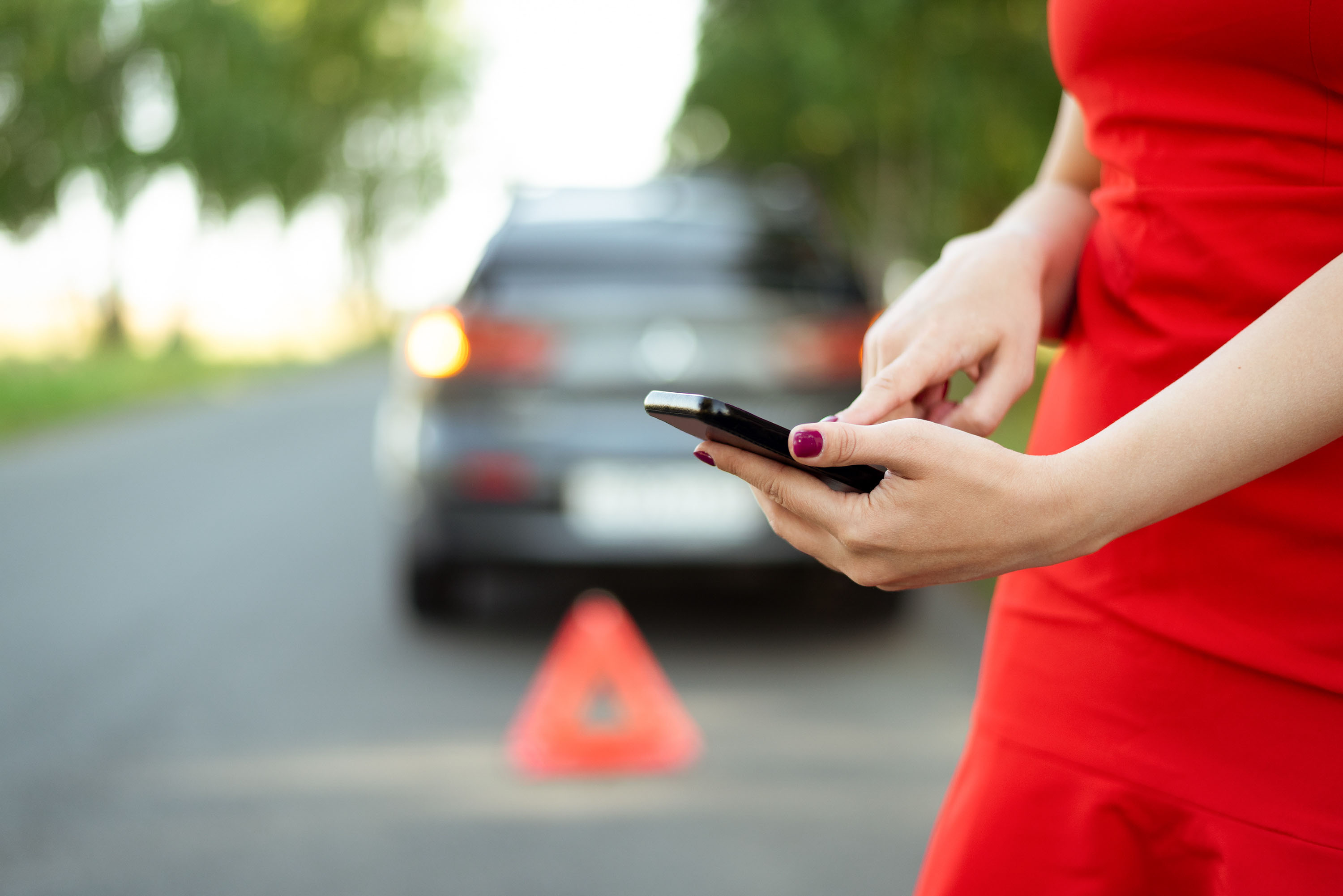 woman calling roadside assistance by her disabled car on Texas highway