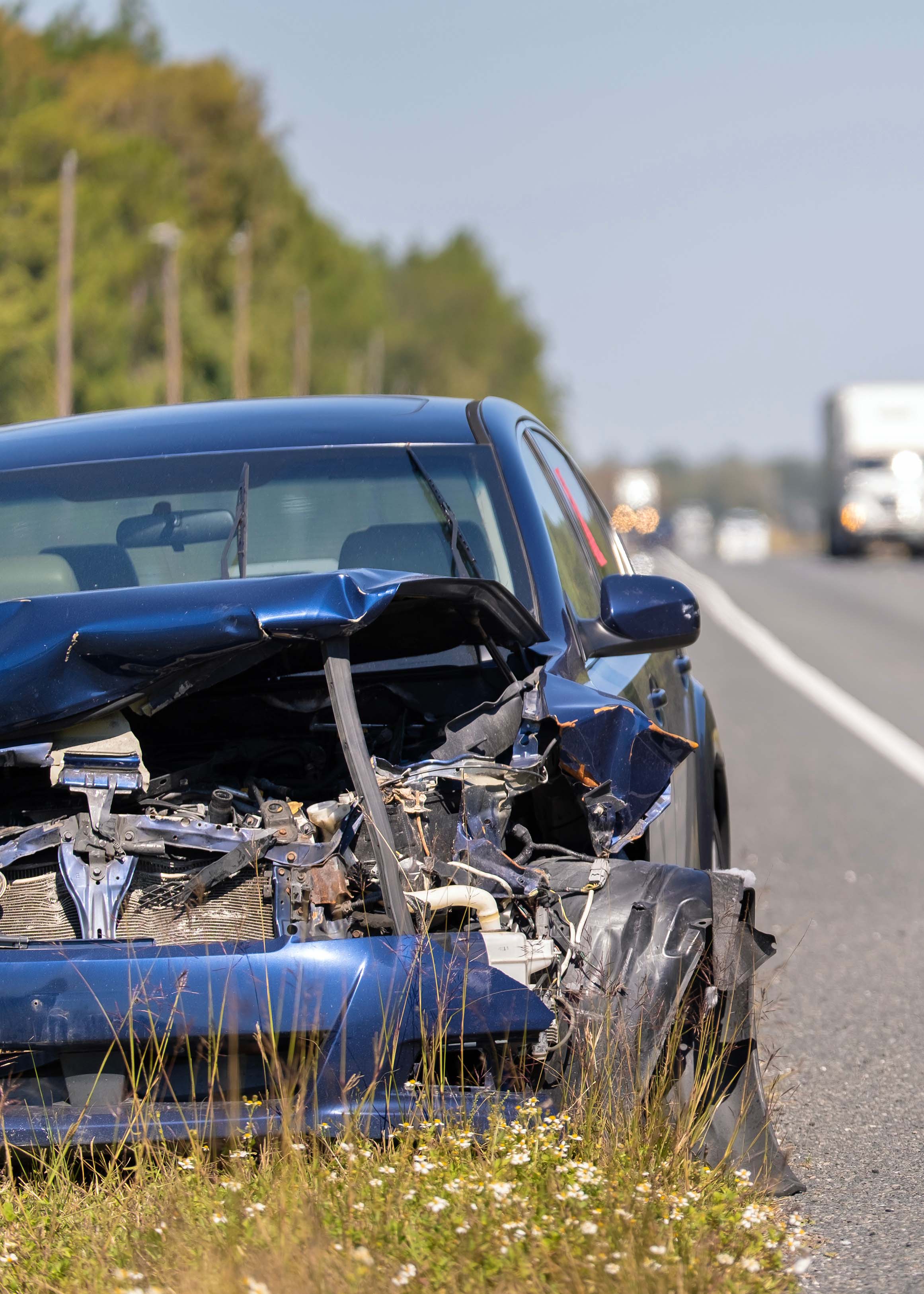 front end of wrecked sedan on highway shoulder after collision