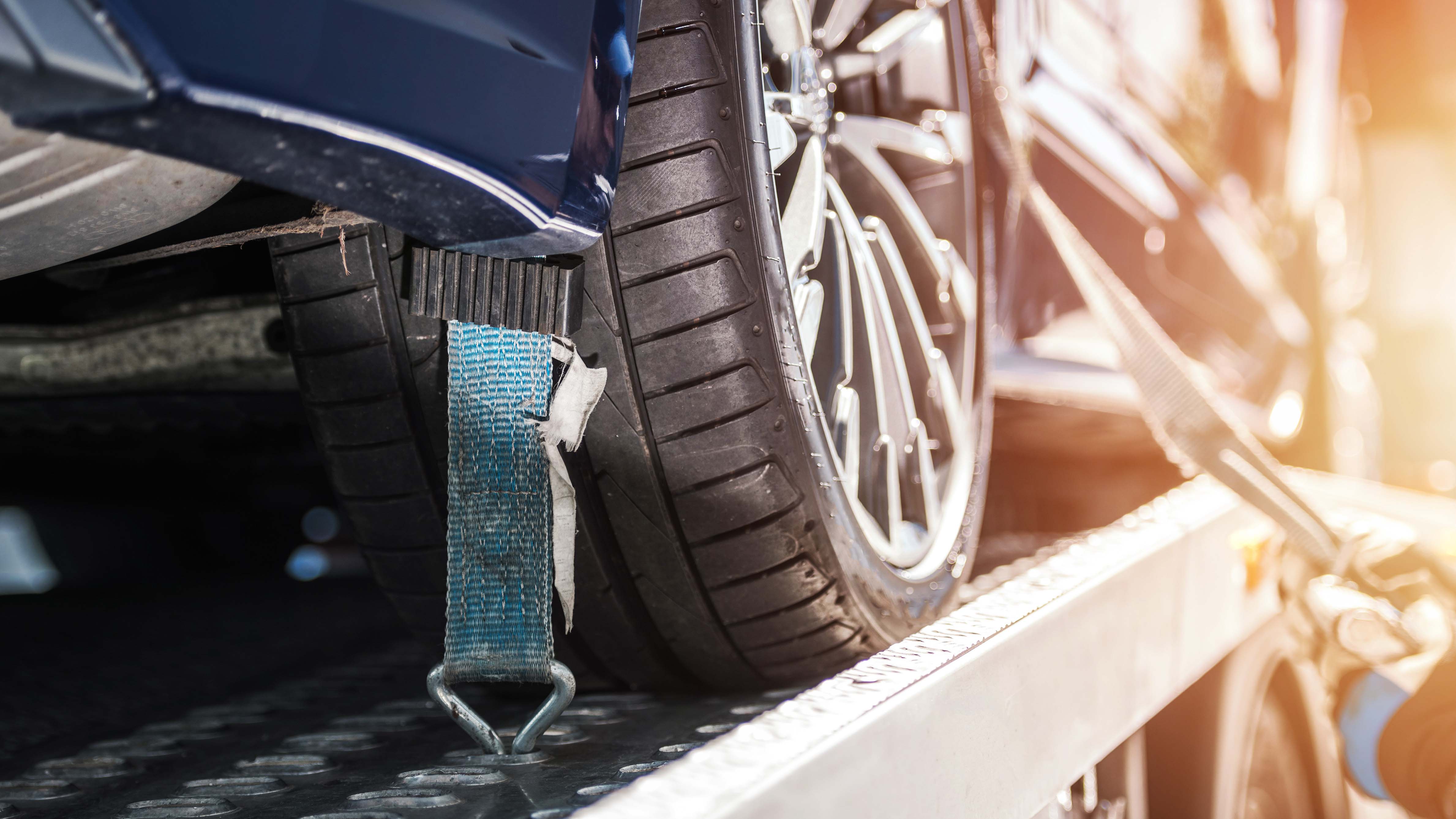 a car fastened with straps on flatbed tow truck