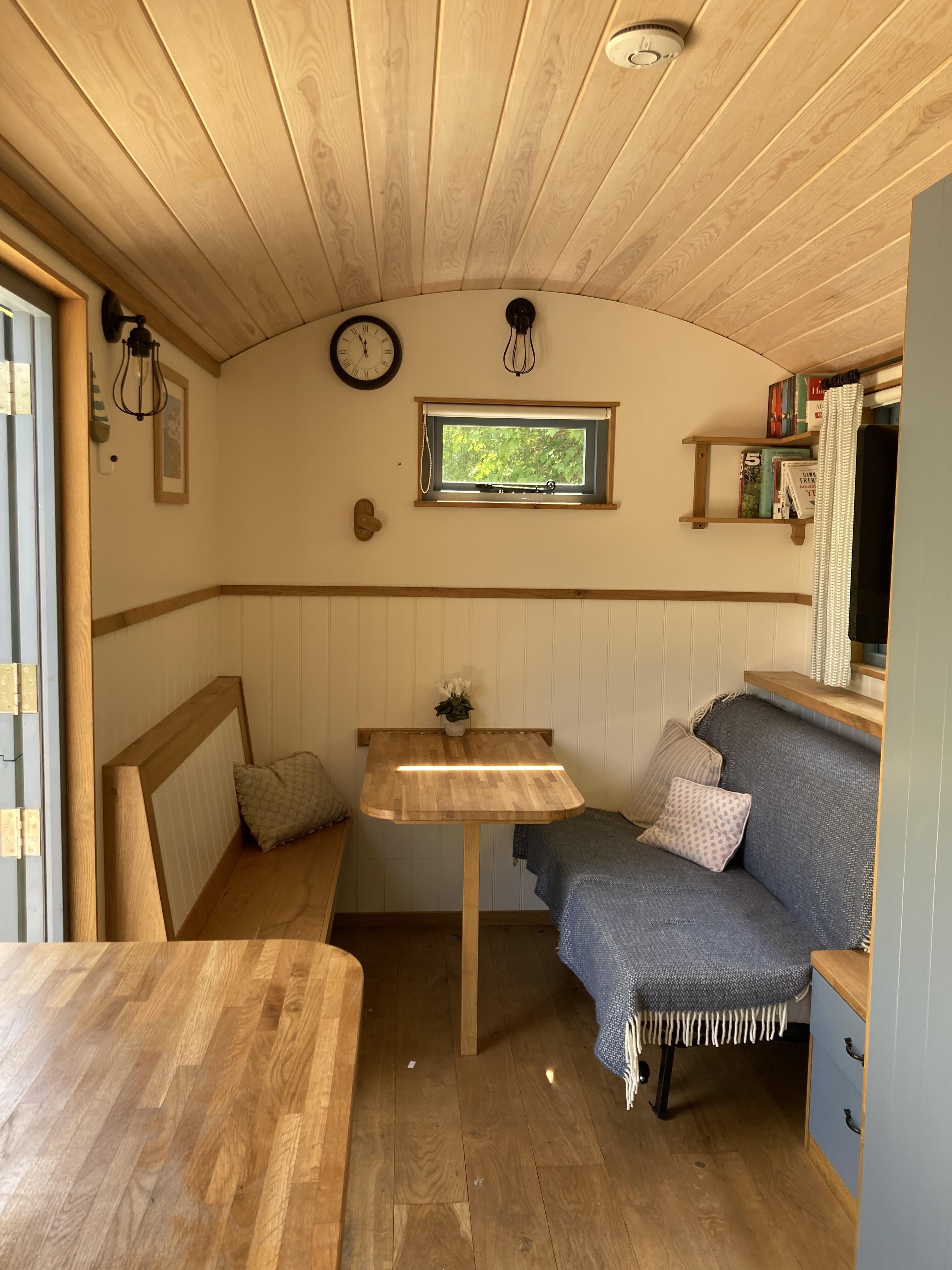 Daytime seating and a small dining table beneath the hut’s curved timber ceiling.