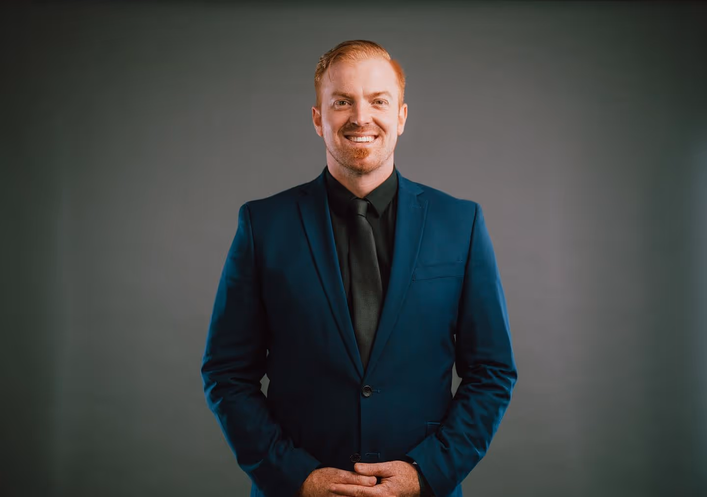 Andrew wears a blue suit against a gray background. He has a radiant smile and looks happy—ready to share the message of Jesus!