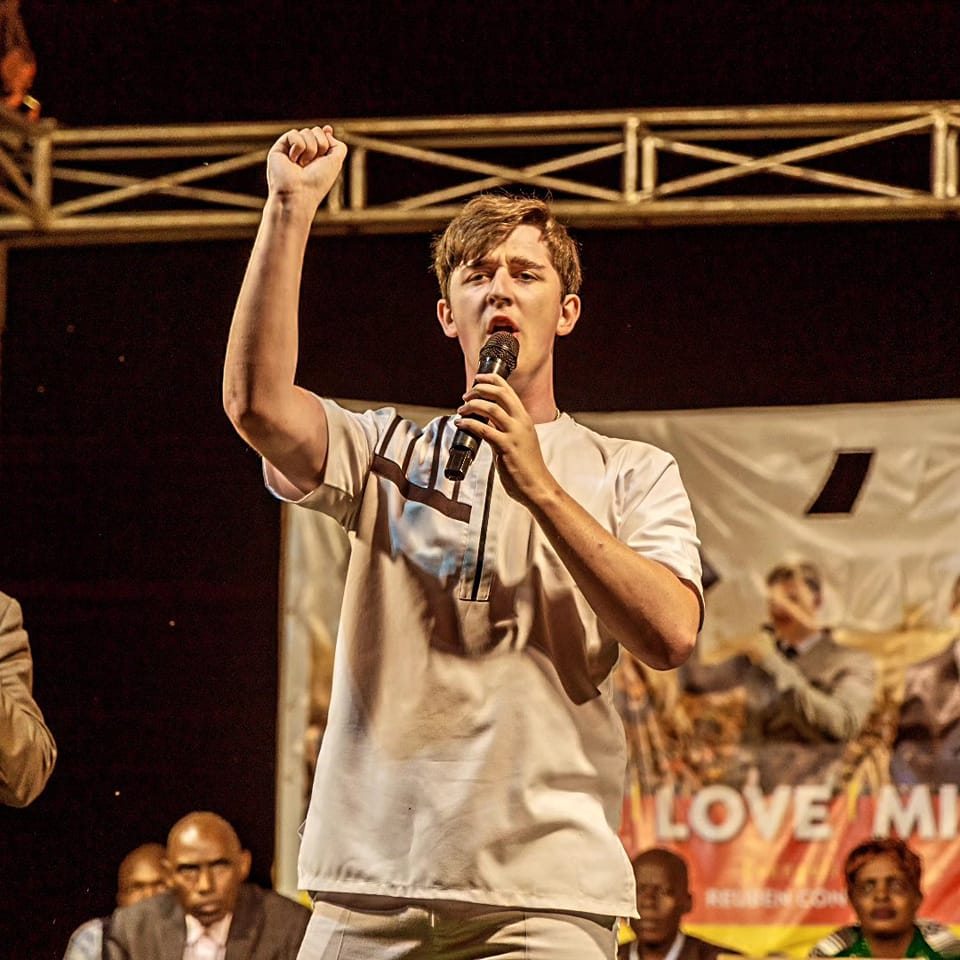 Reuben stood on stage with a microphone, passionately proclaiming Jesus Christ to the crowd.