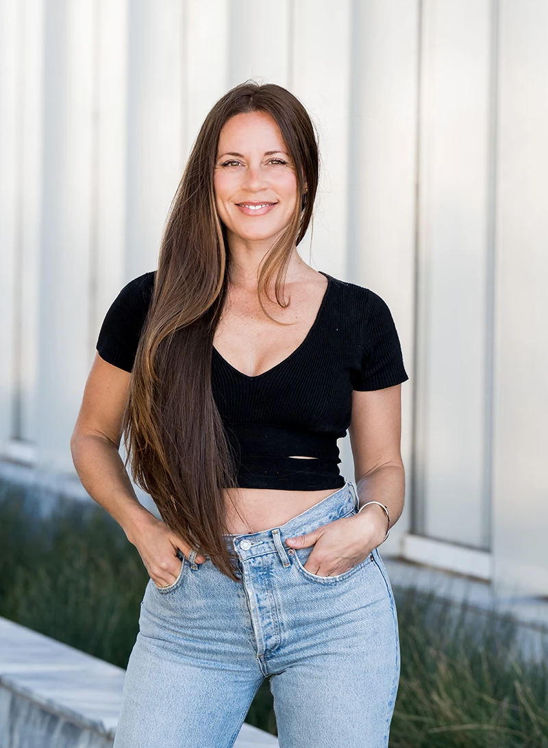Kahlah, in a black shirt and jeans, standing and smiling
