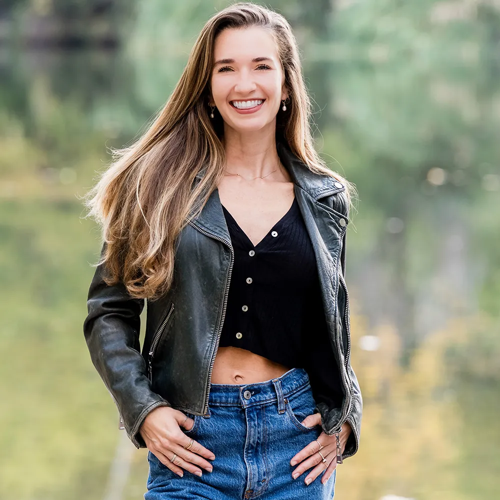 Photo of Sydney wearing a leather jacket and black top, smiling