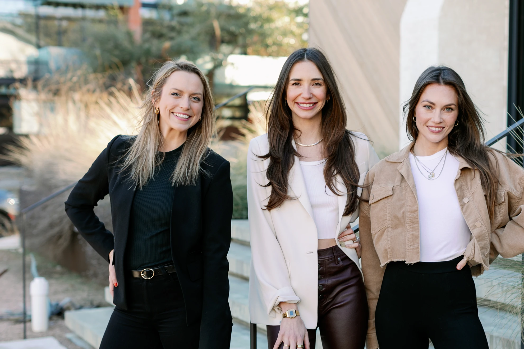 Photo of Blaine in a light tan blazer, standing between her teammates Kailey and Michaela.