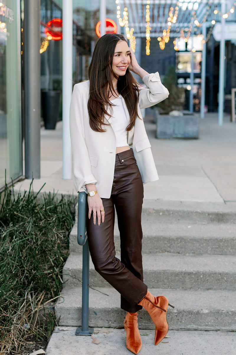 Blaine, wearing a white button-up shirt and beige skirt, standing indoors, smiling.