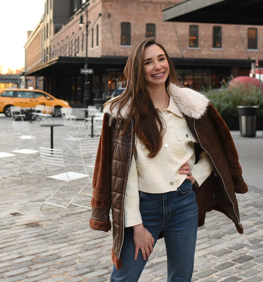 Blaine, smiling, holding a white cup seated at a red café table with croissants.