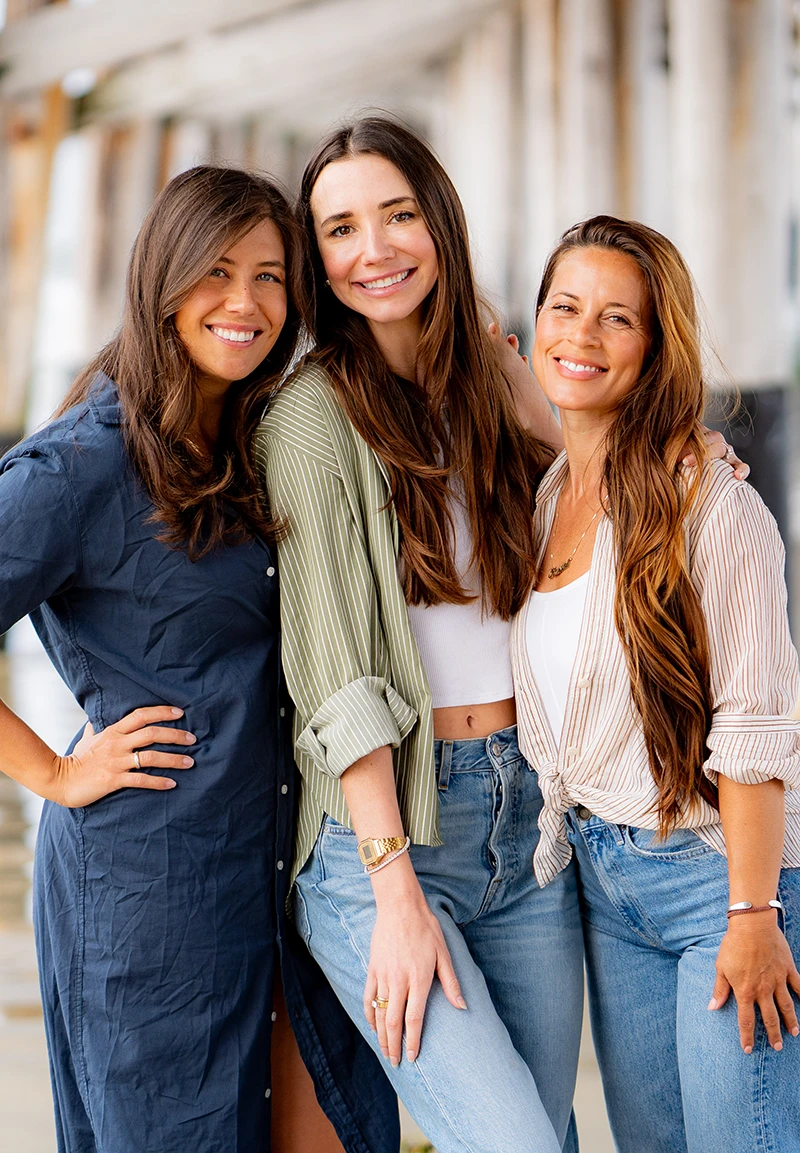 Blaine, smiling, holding a white cup seated at a red café table with croissants.