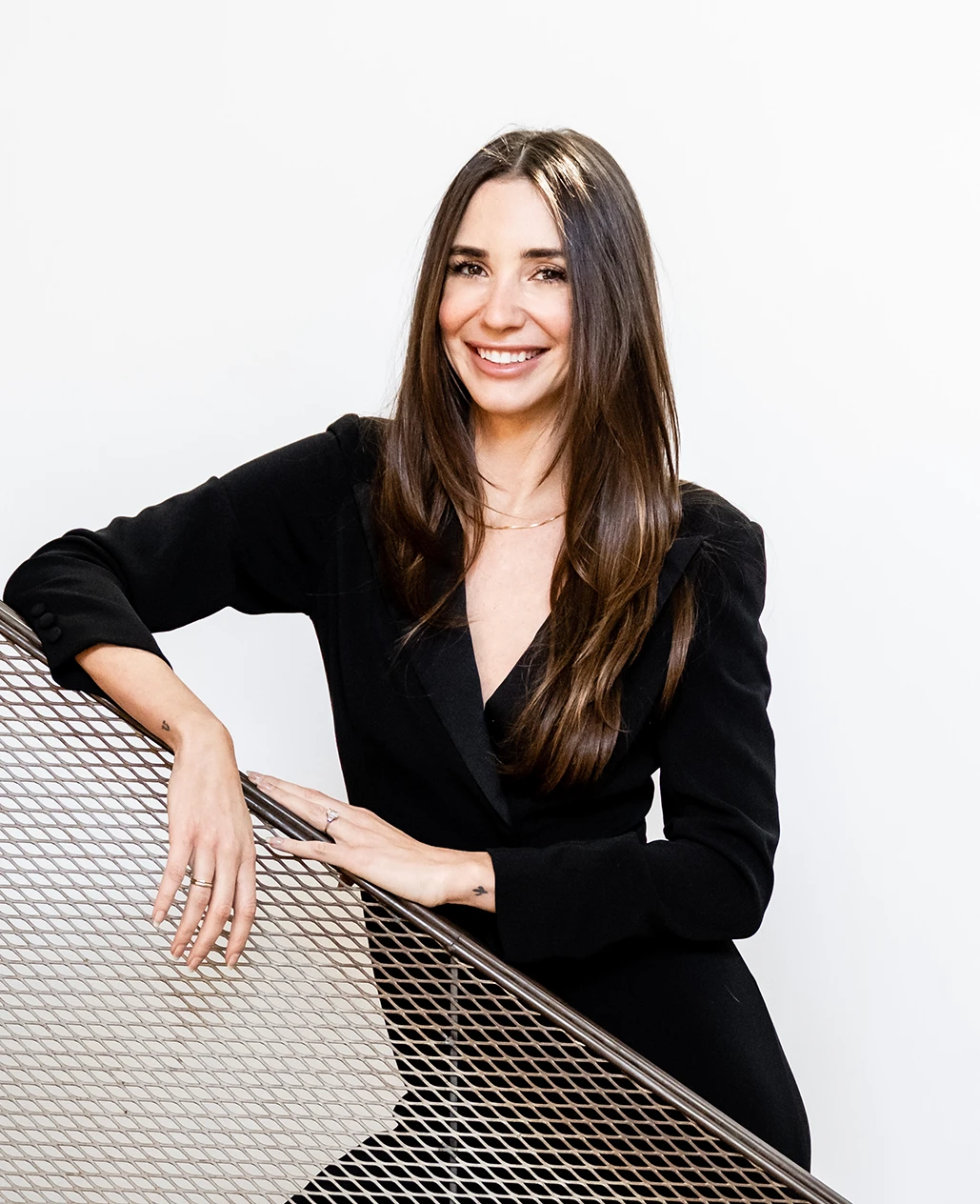 Blaine, smiling, holding a white cup seated at a red café table with croissants.