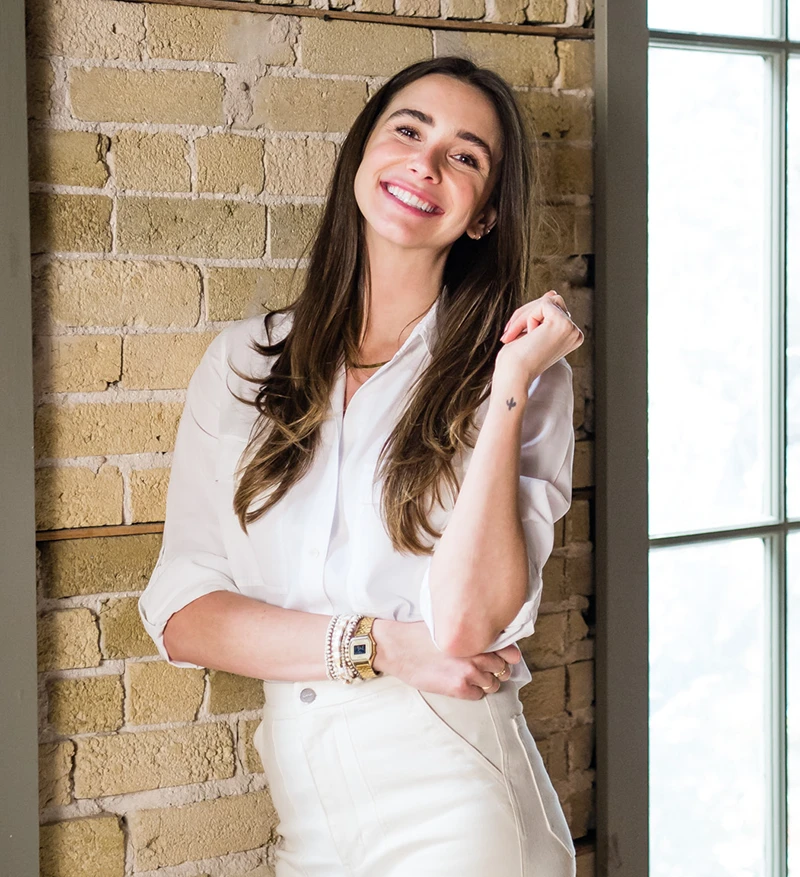 Photo of Blaine in a white top and white jeans in a loft, smiling