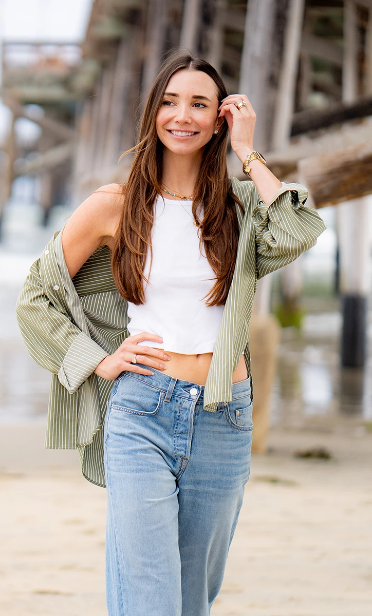 Blaine, smiling, holding a white cup seated at a red café table with croissants.