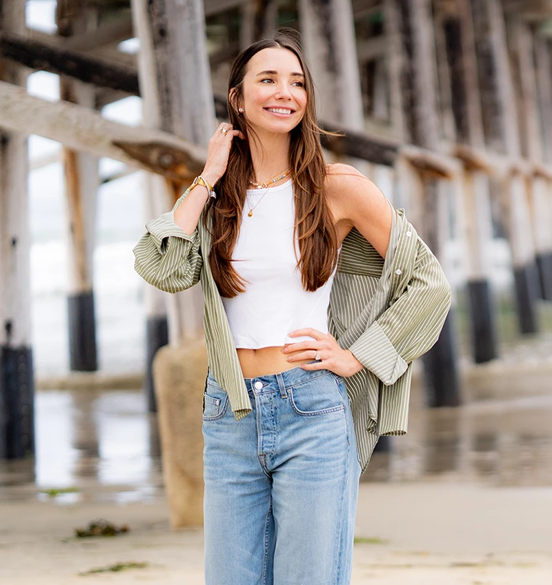 Photo of Blaine wearing a green shirt, light jeans, walking on the beach