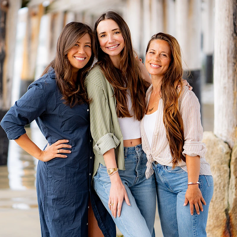 Blaine, wearing a white button-up shirt and beige skirt, standing indoors, smiling.