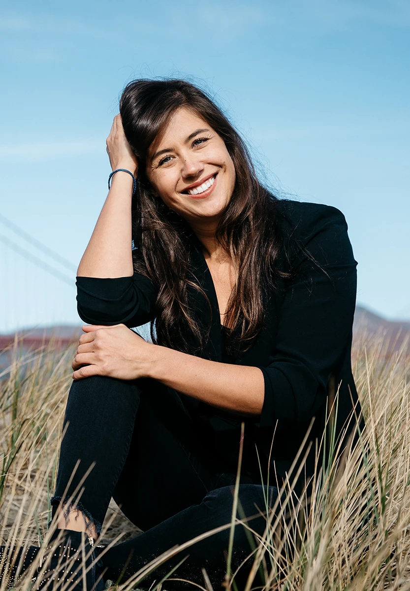 Blaine, smiling, holding a white cup seated at a red café table with croissants.