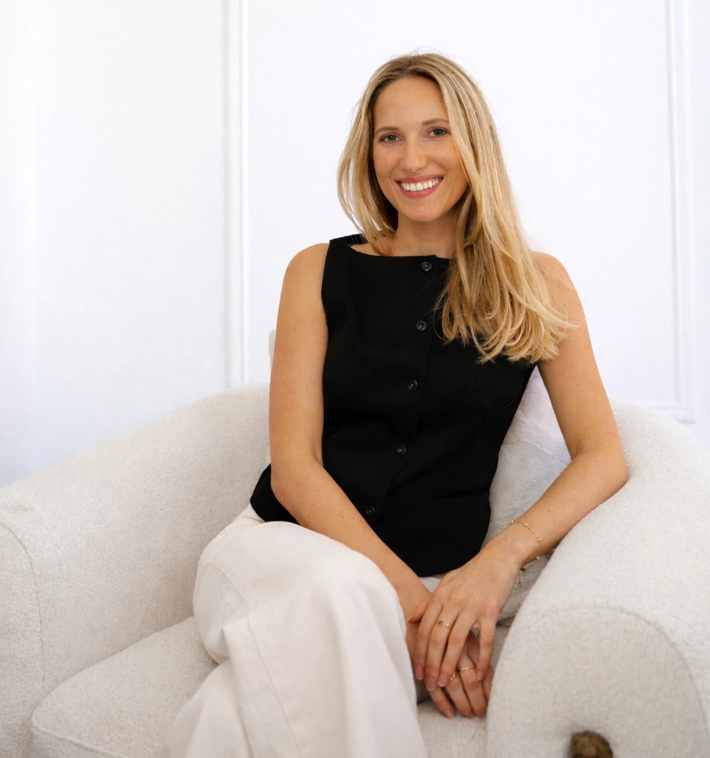 Photo of Brianna, wearing a black shirt, seated in a white chair, smiling