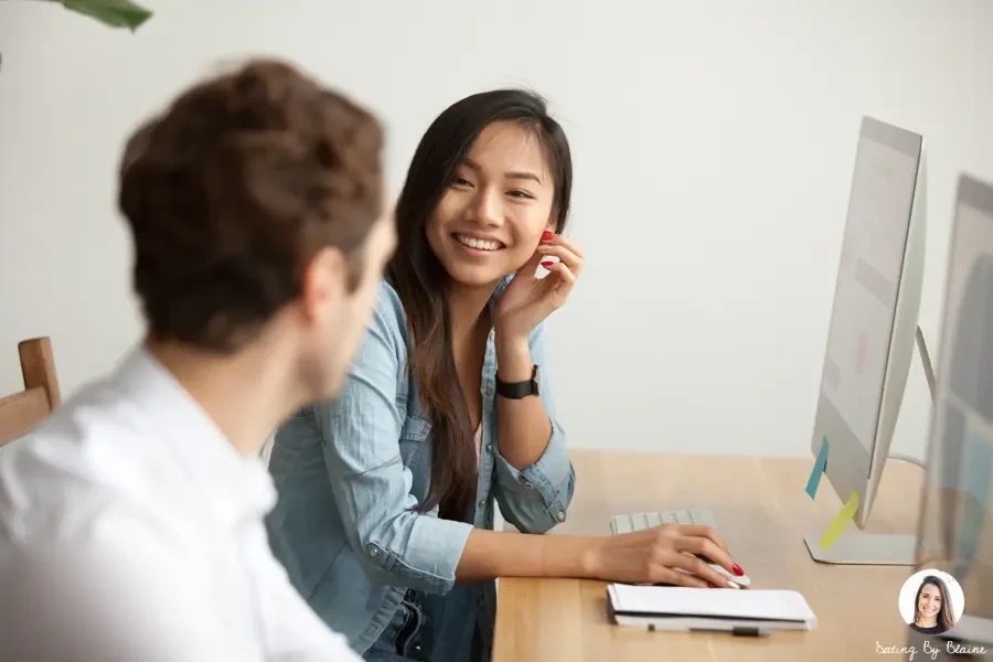 A woman smiling next to the guy beside her, while they are in the computer