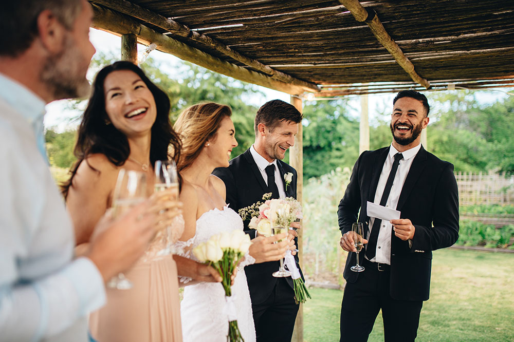 Group of men and women smiling in nice outfits at a wedding