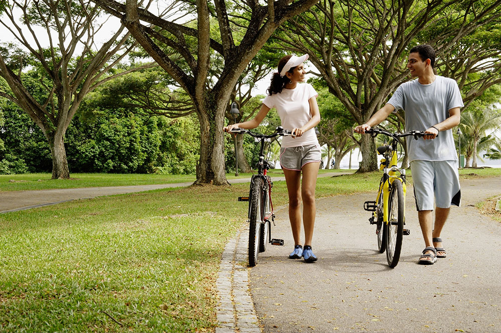 Couple walking with bikes through a park