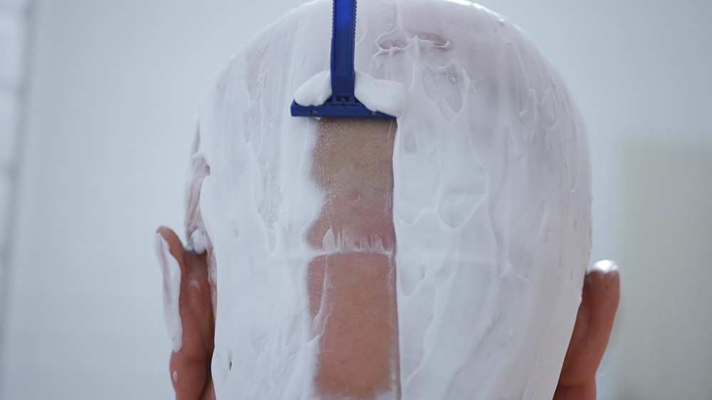 Man shaving his head in the shower