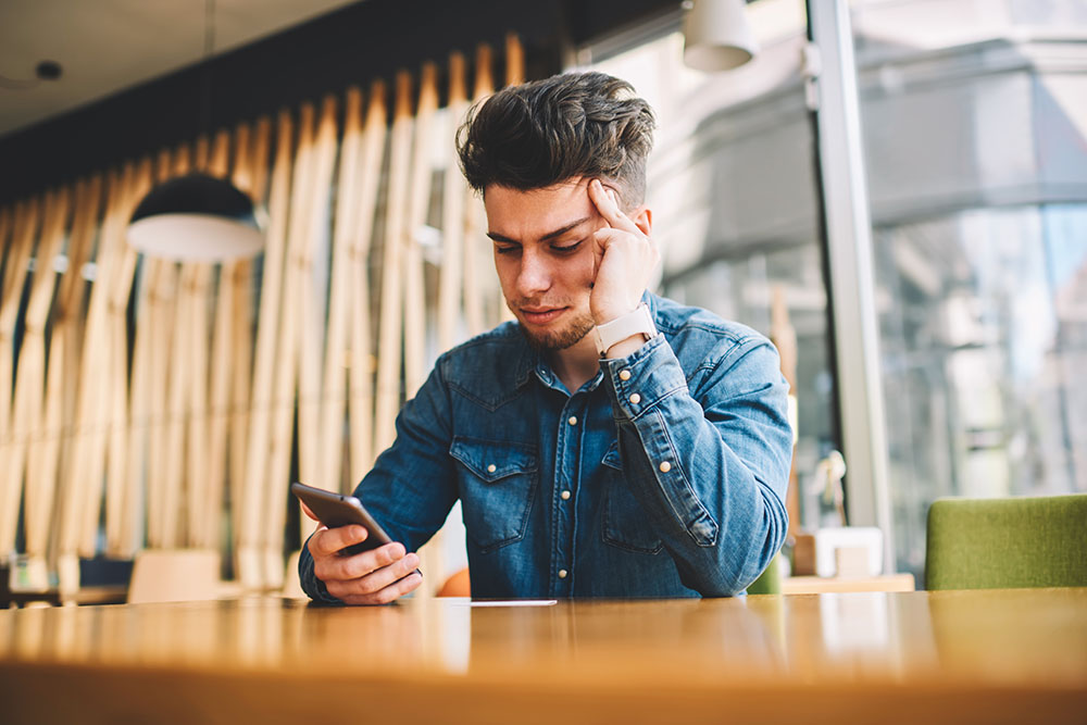 Man looking at phone with pensive face