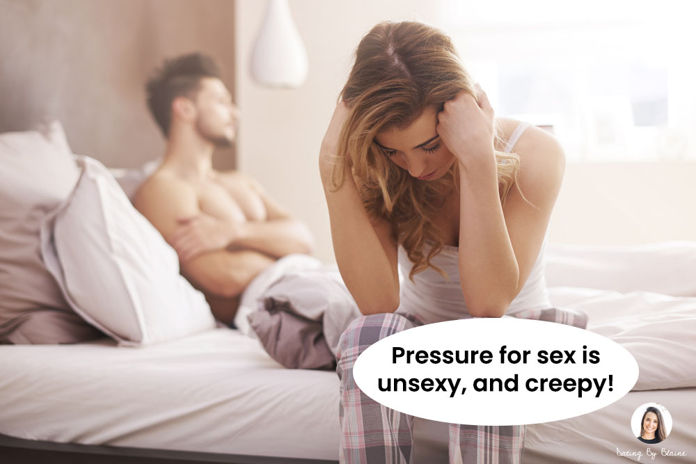 Woman in pajamas, seated on edge of bed, looking disappointed, with man looking away with possibly frustrated expression, also on bed, in background