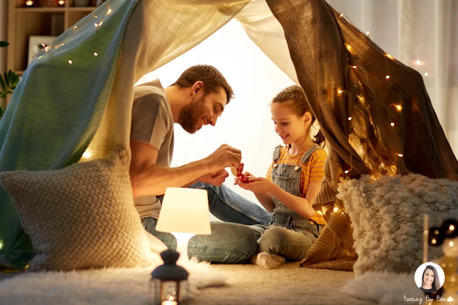 Man playing with his daughter in a tent in their living room
