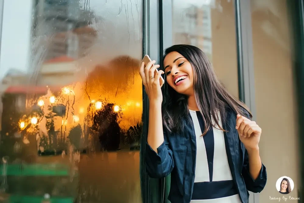 a girl leaning to a glass door, smiling while texting