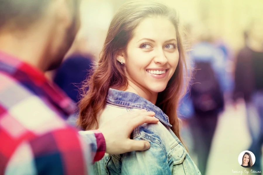 Woman smiling and looking back at man, who has his arm outreached and is touching her shoulder