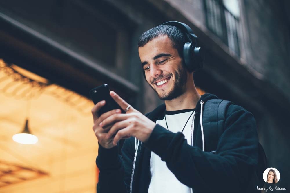 A guy holding his phone or texting and smiling