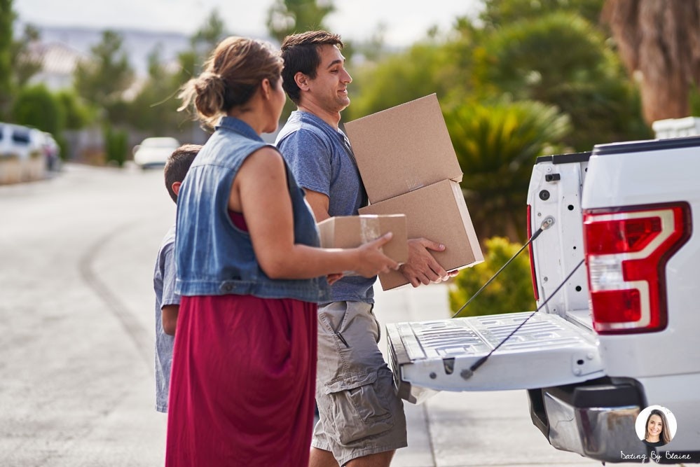 A man lifting boxes into the back of a truck, with a woman standing next to him