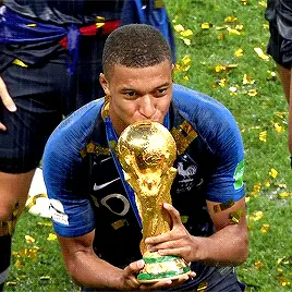 Soccer star Kylian Mbappé raising a gold trophy