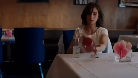Gif of a woman spilling a glass of red wine onto a white tablecloth