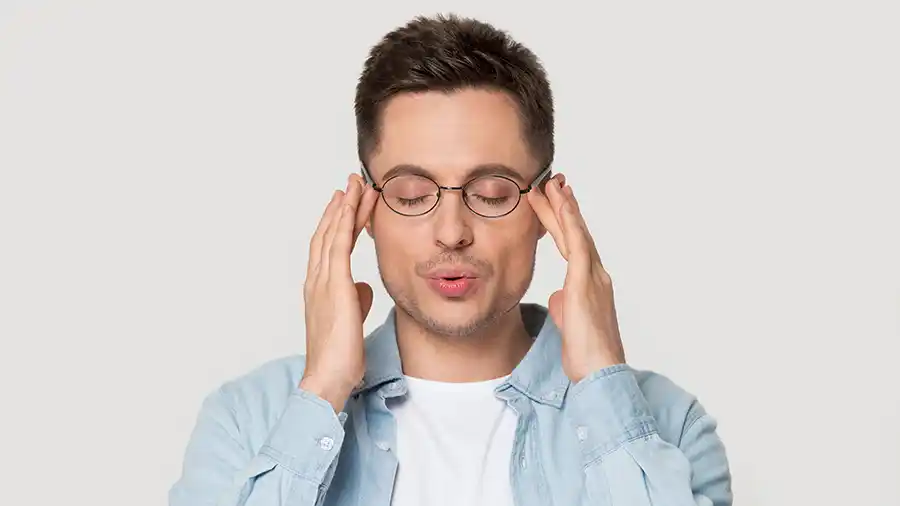 A man touching his temples, looking like he's relaxing from stress