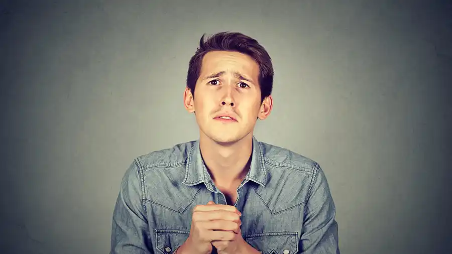 A man in a jean shirt with a pleading look on his face