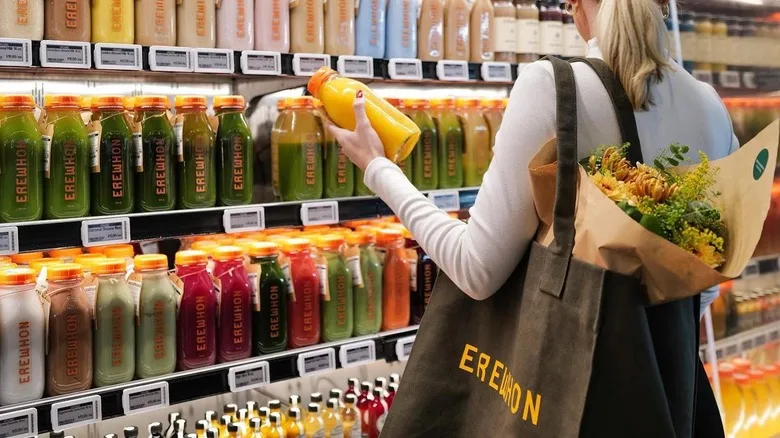 Photo of a woman holding a juice at an Erewhon grocery store
