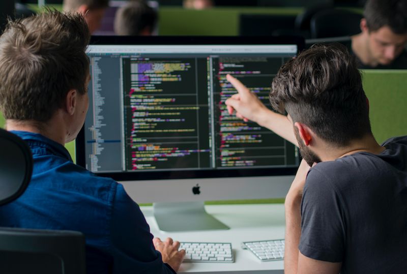 Developers reviewing code on a computer monitor.