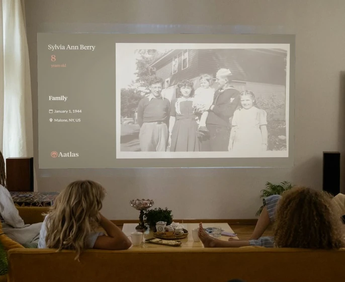 A family in a living room watching an Aatlas slideshow on a projector