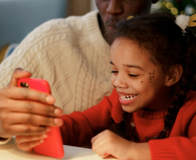 A father and daughter at a holiday table, sharing a phone