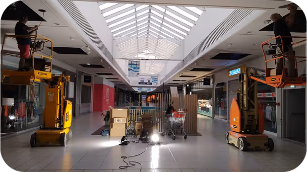 une allée d'un magasin avec un employé max et vous sur une machine qui répare quelque chose dans le plafond