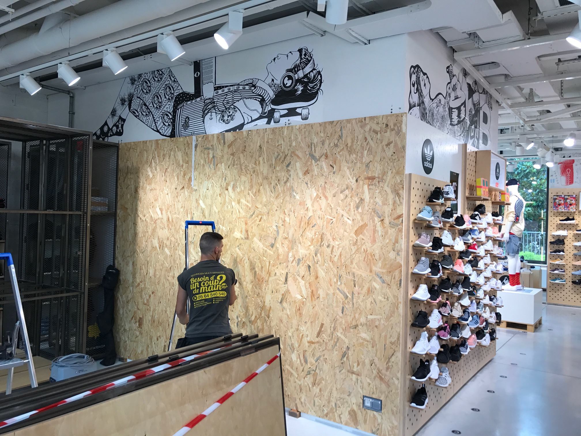 une photo d'un employé dans un magasin qui est en train de faire des travaux sur un mur