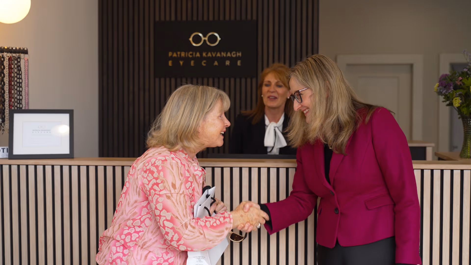 Women shaking hands at Patricia Kavanagh Eyecare reception desk