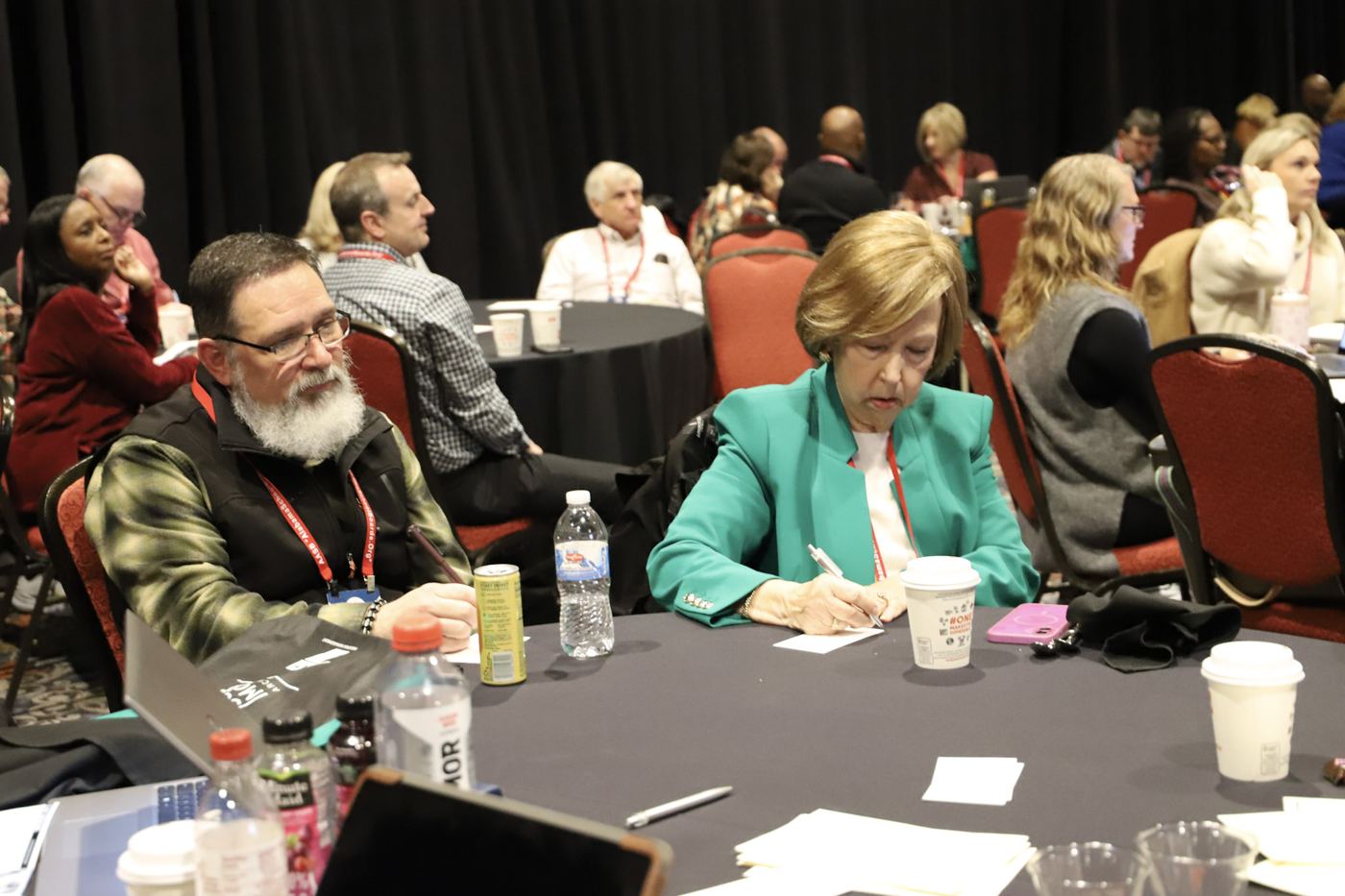 Educators writing at their tables during a conference keynote