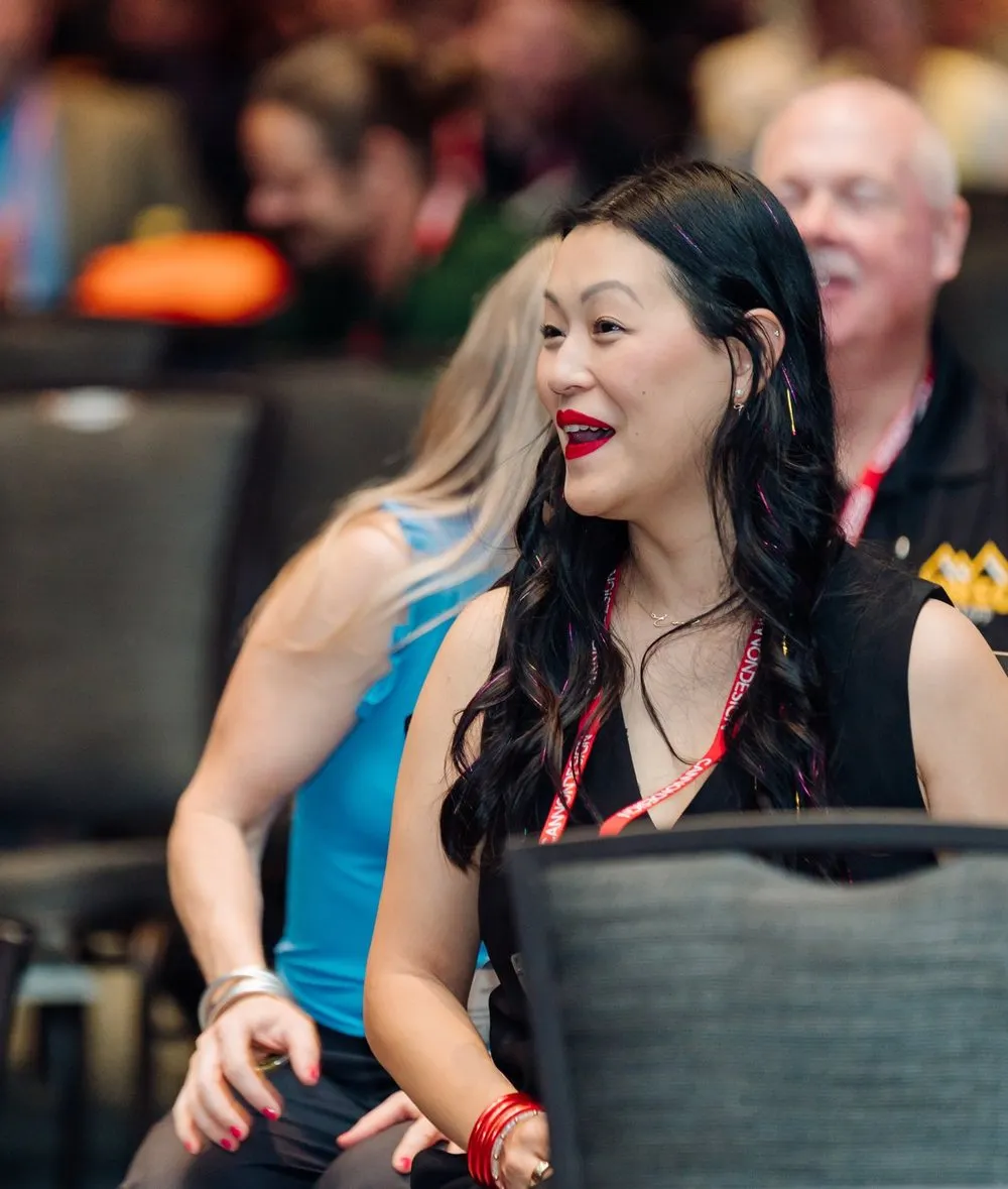 An attendee laughing with her table during Darryl Bellamy Jr.'s keynote