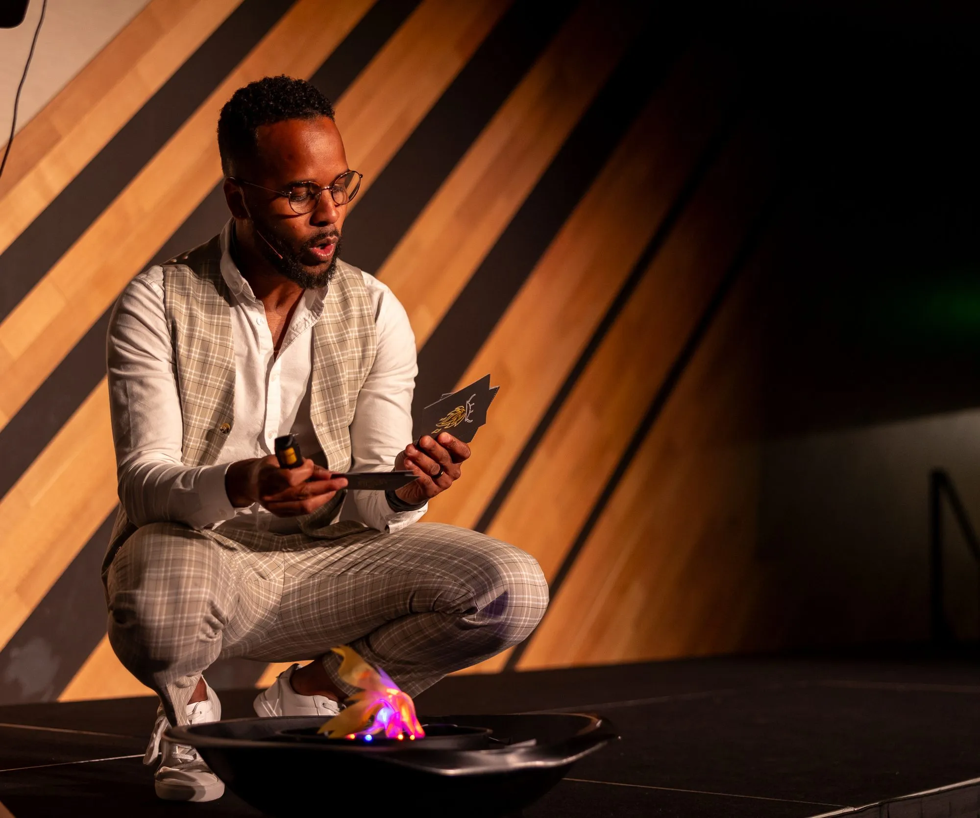 Darryl on stage reading a fear card by the fire pit