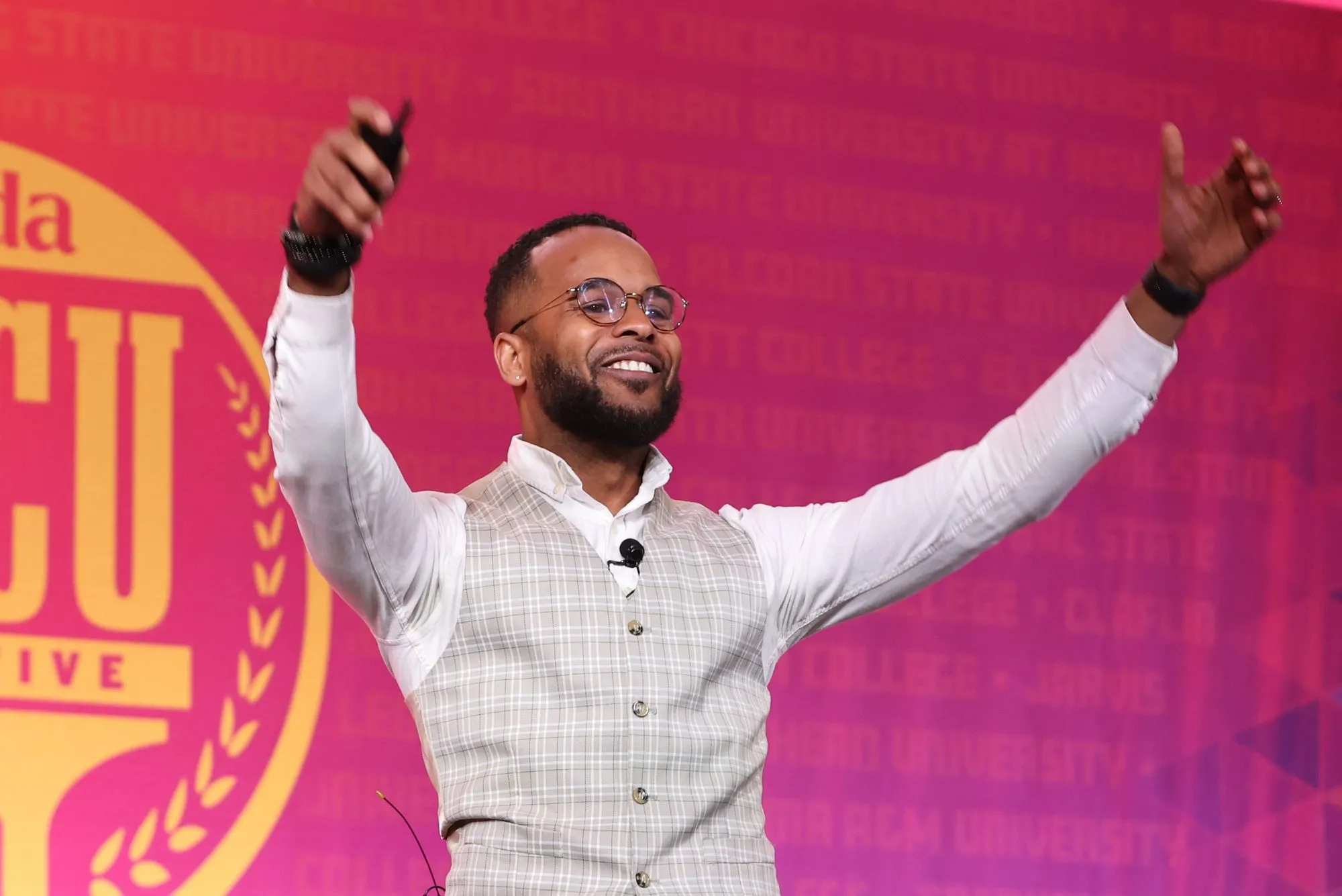 Darryl with his arms up on stage at Strada's HBCU Initiative