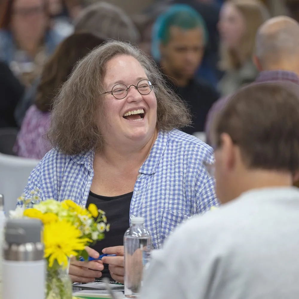 An educator laughing at her table during a keynote